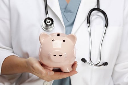 Closeup of a doctor holding a piggy bank