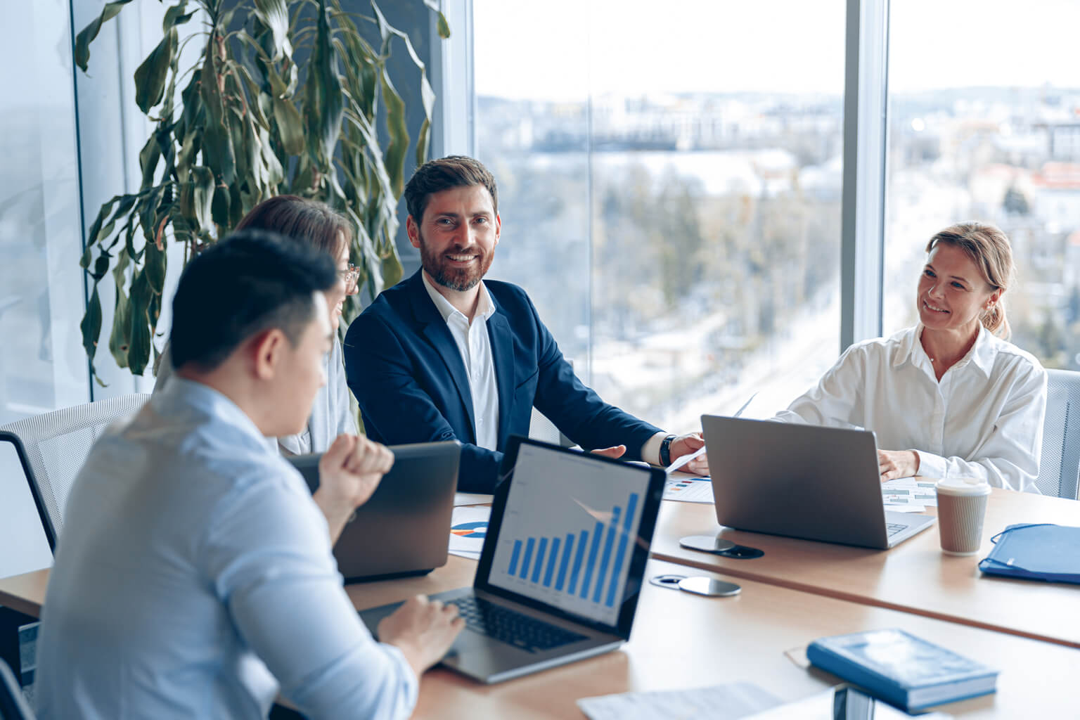 Three people sitting at a conference table with laptops open