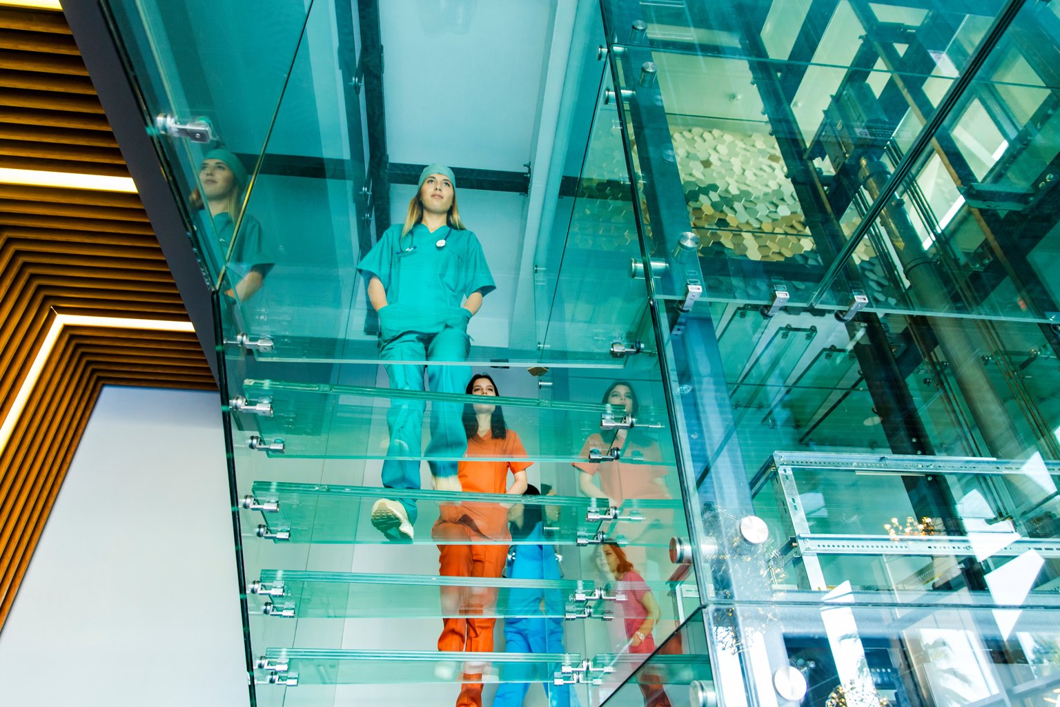 Group of nurses walking up glass stairs in hospital