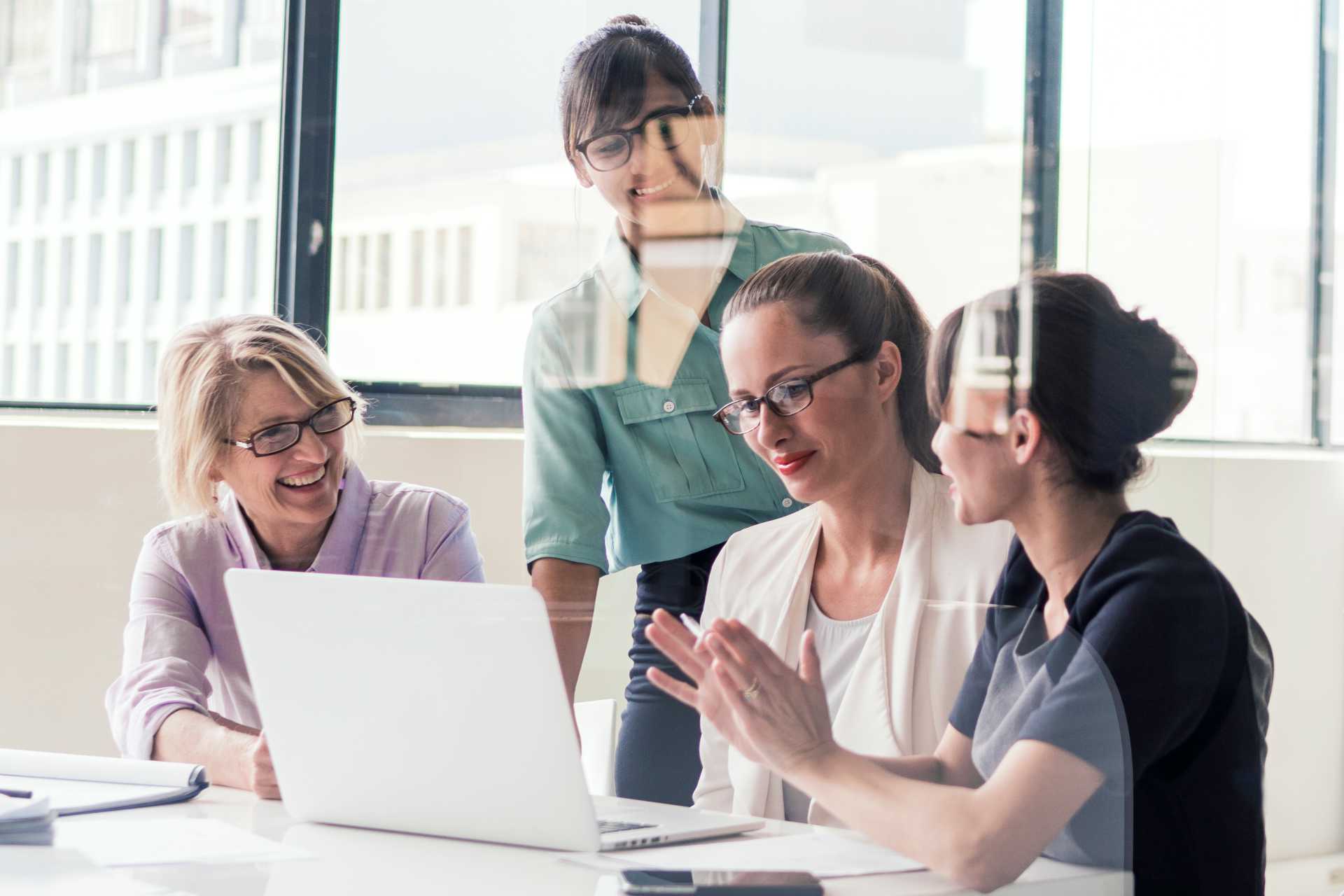 Group of women in office meeting around a laptop