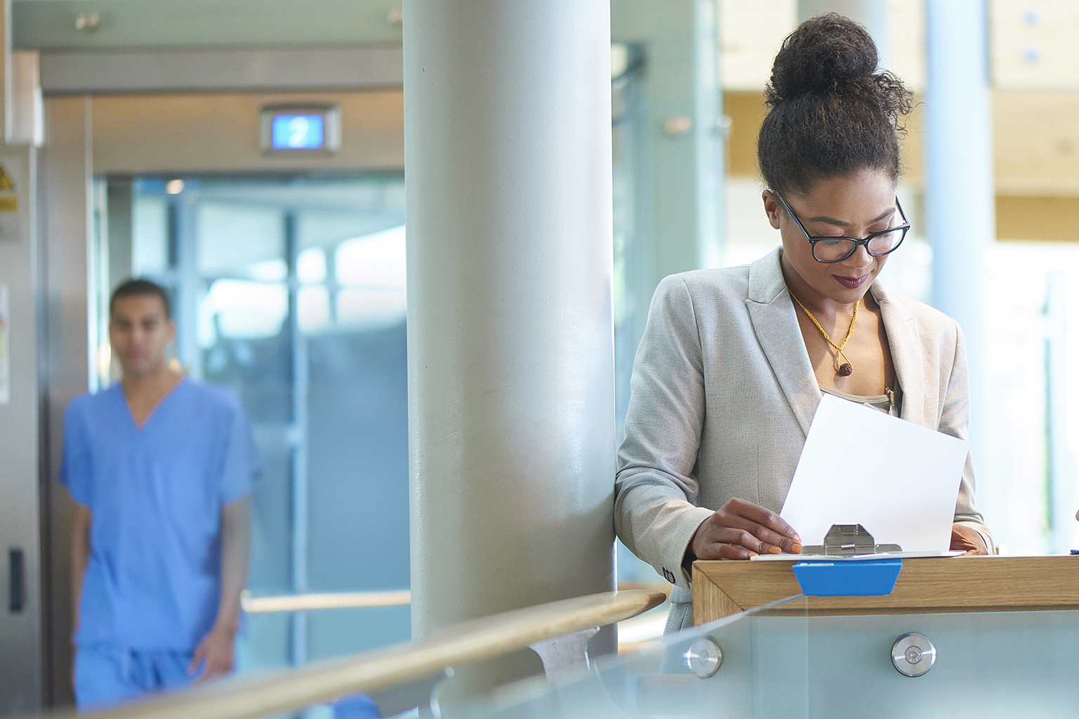 Nurse leader looking at clipboard at hospital lobby desk