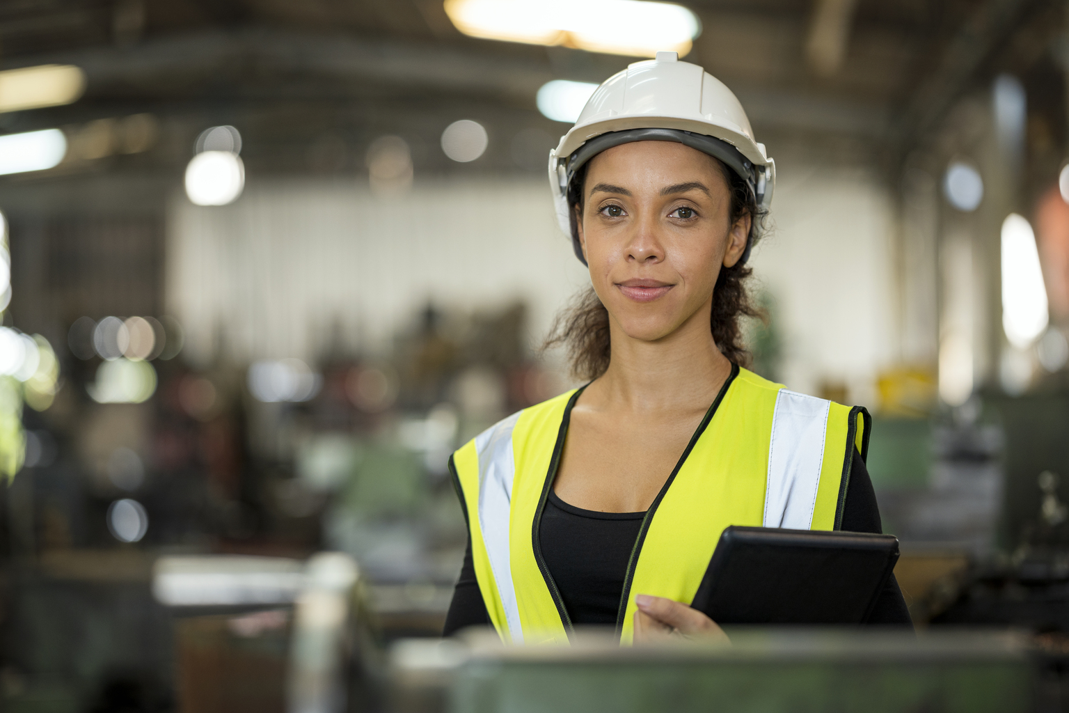 Portrait of female machinery factory owner with digital tablet while standing in workshop