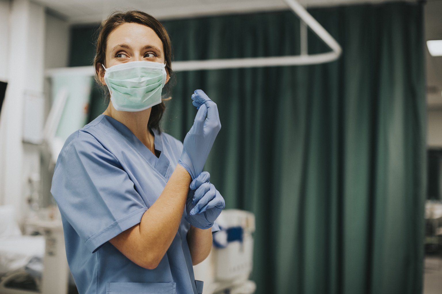 Nurse wearing mask and scrubs, putting on gloves