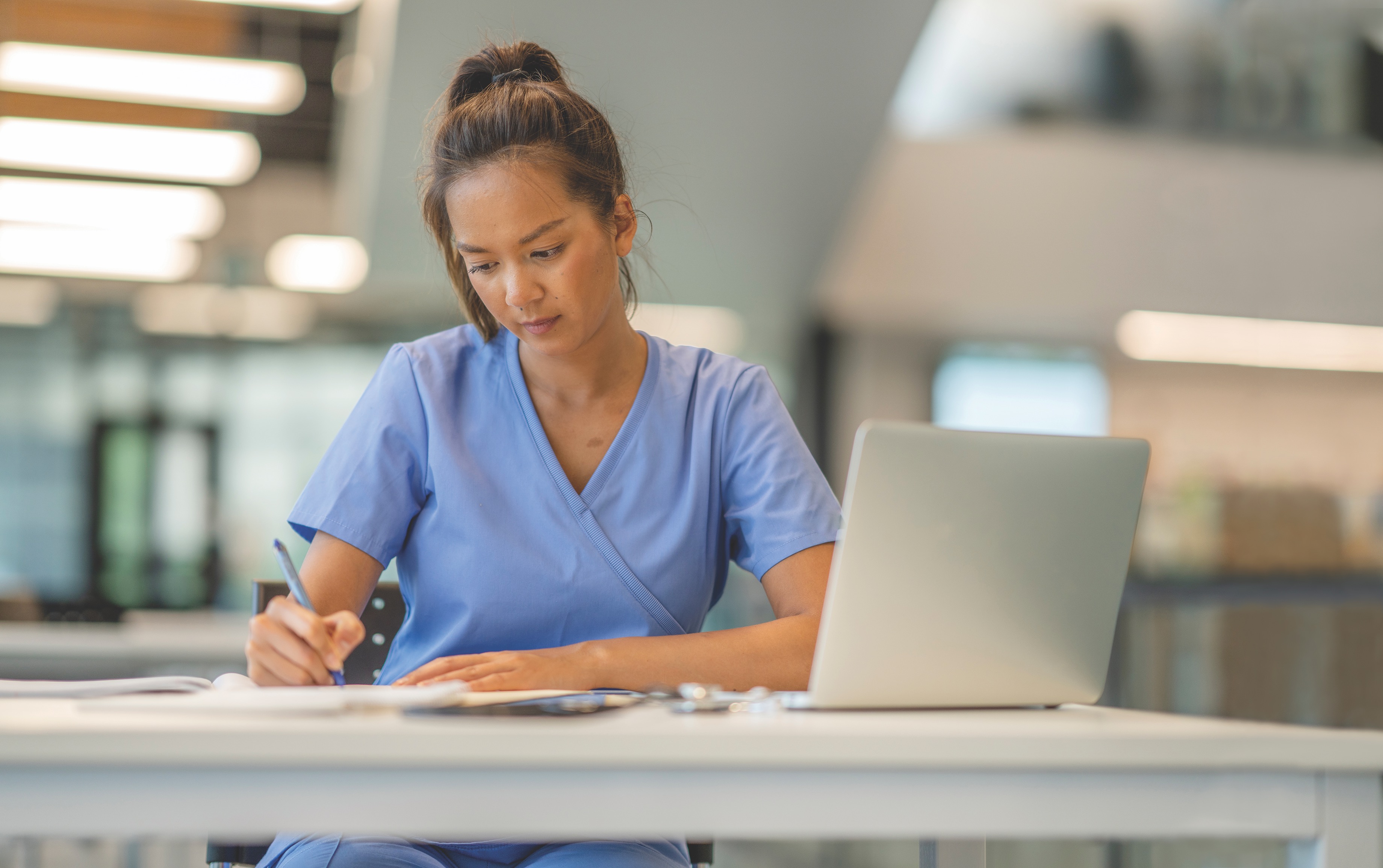 Nurse working at table with laptop