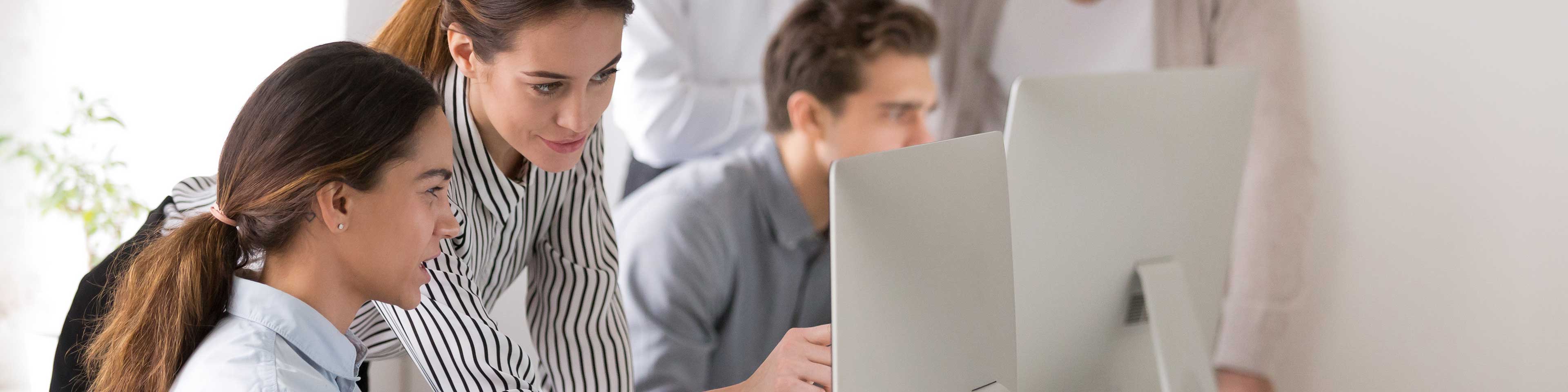 Women and man looking at laptops