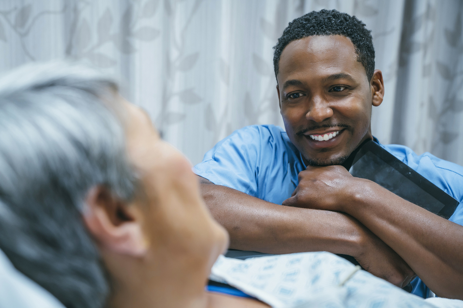 <p>Nurse talks with patience in hospital bed</p>
