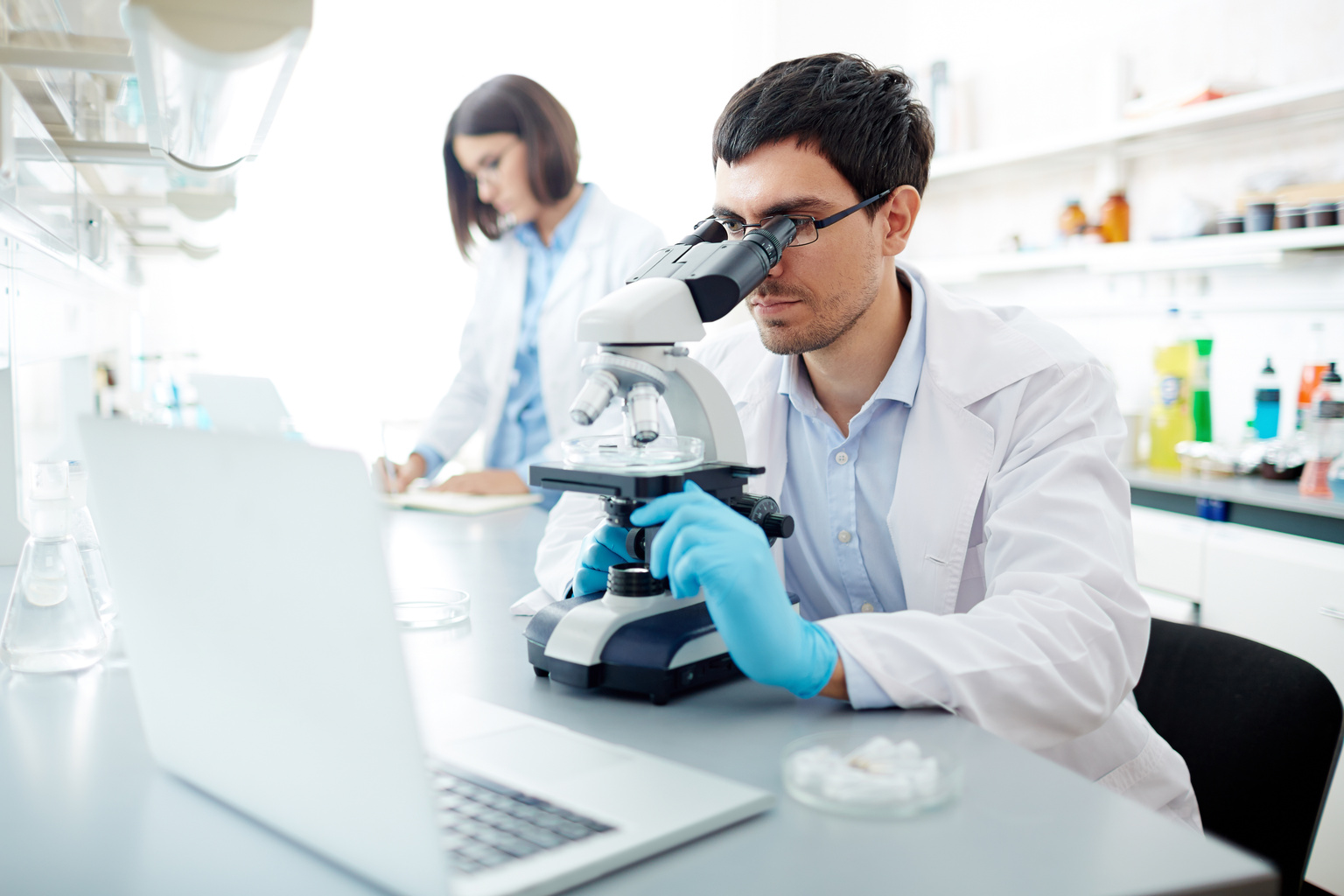 Lab worker looking in microscope at work