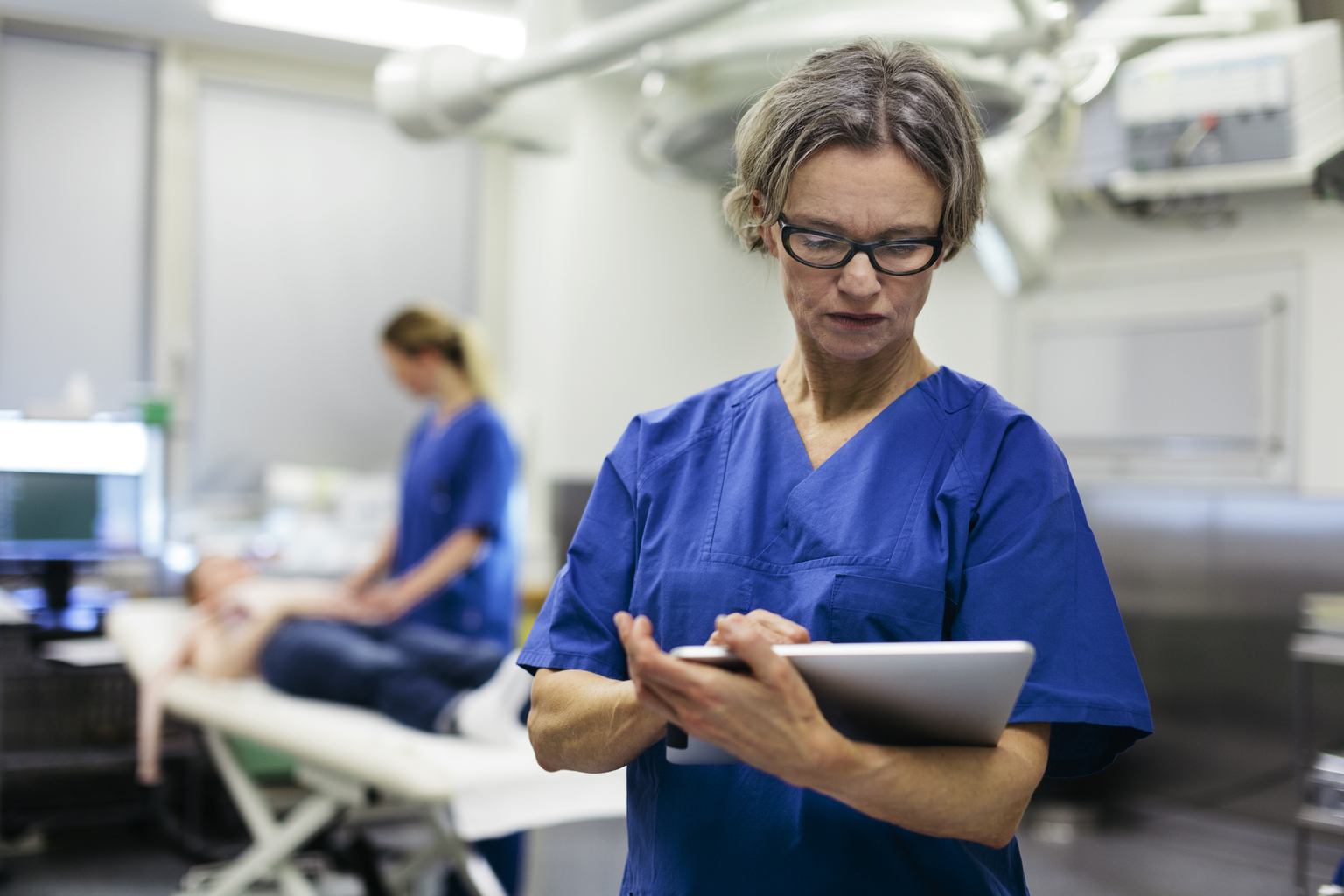 White female doctor with tablet in operating room.