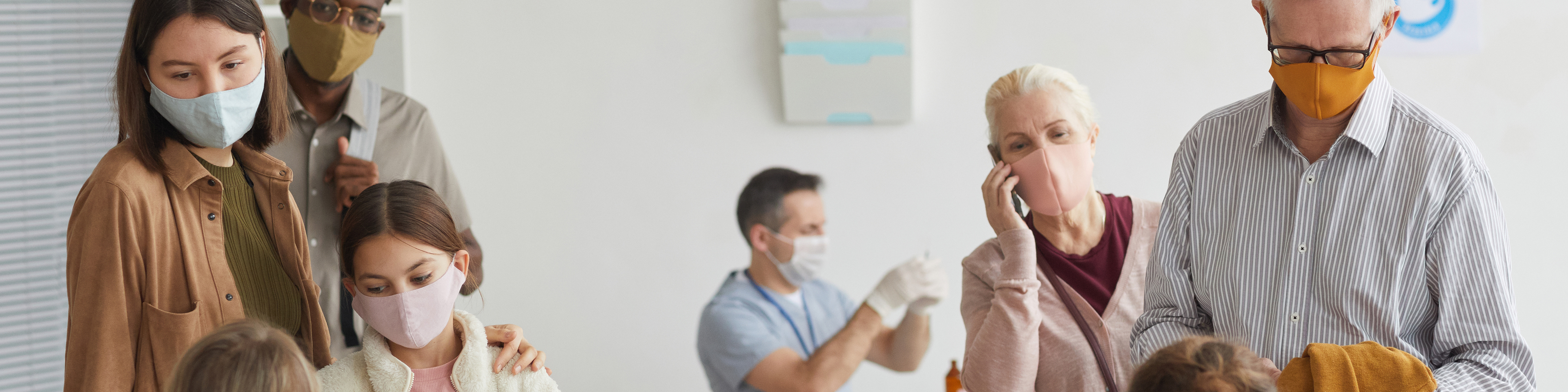 Group of patient wearing face masks, standing in lines at vaccine check in desk