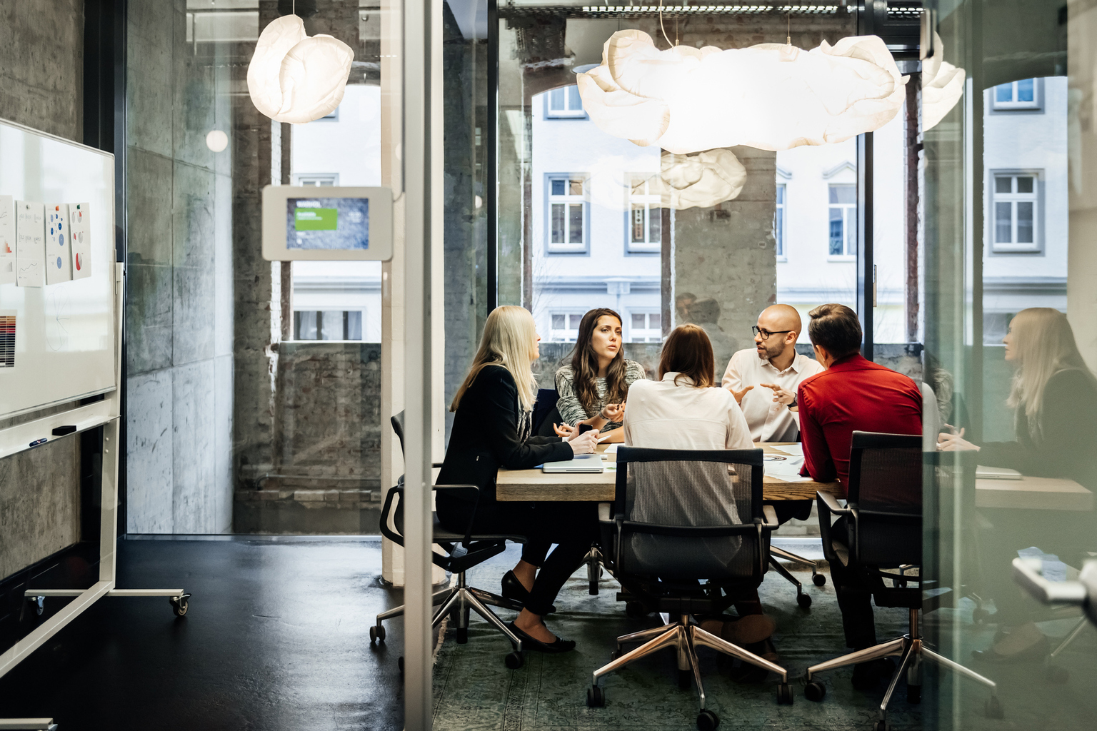 A group of people is sitting at a table during a business meeting in a bright, modern office