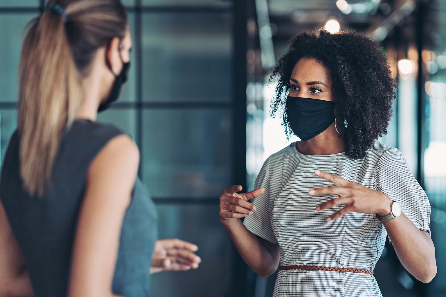 collega's met mondkapjes praten op de werkvloer