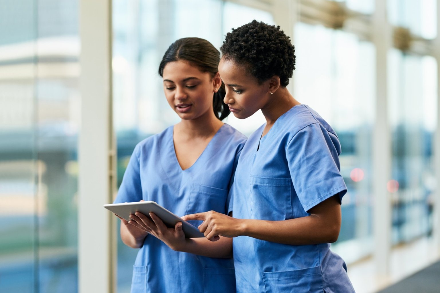 Two nurses conversing looking at a tablet
