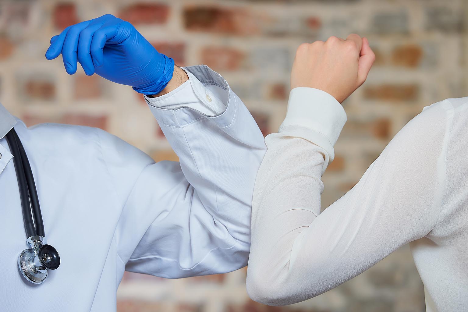 Close up of a physician elbow bumping a business person.