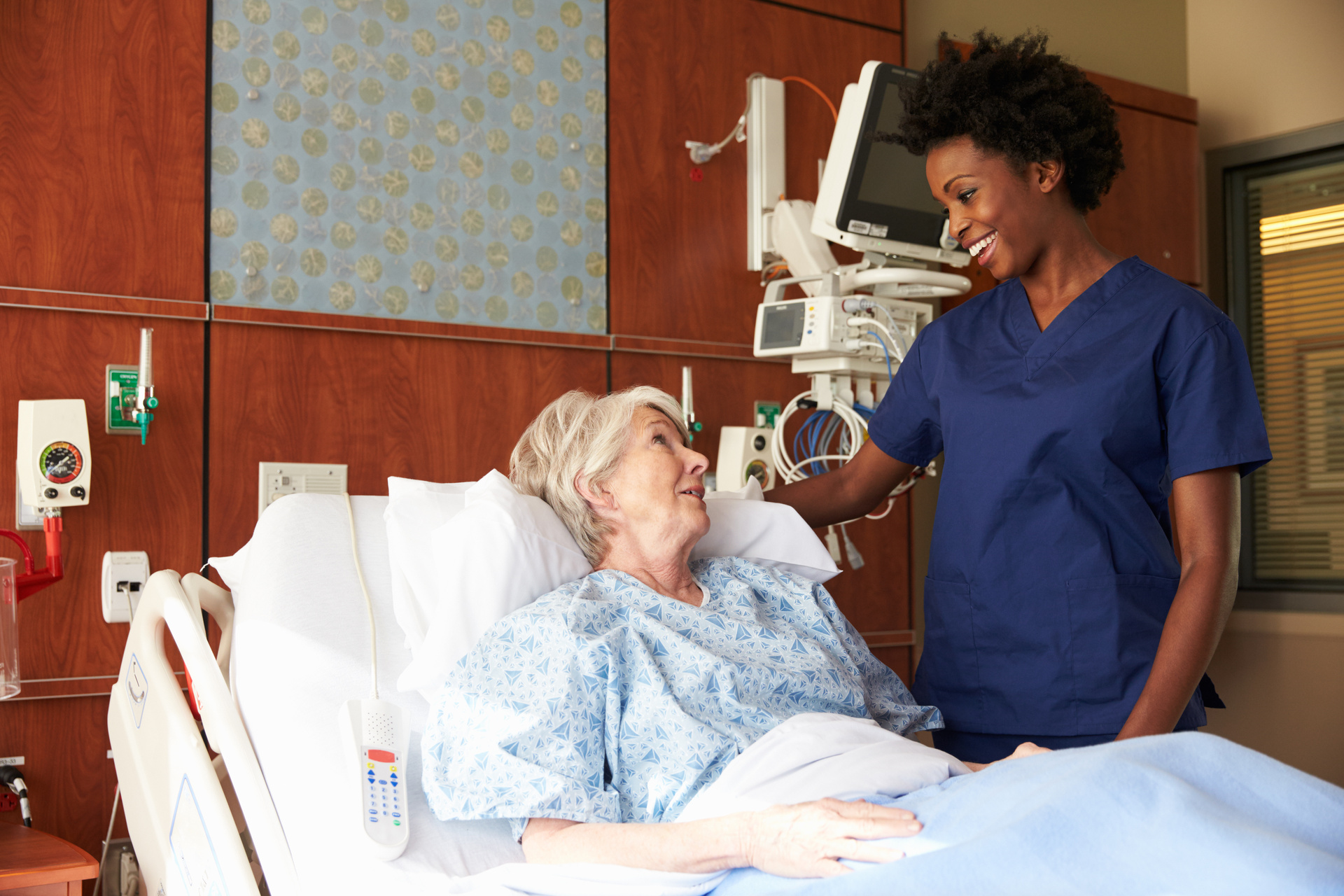Nurse speaking with elder female patient at the bedside