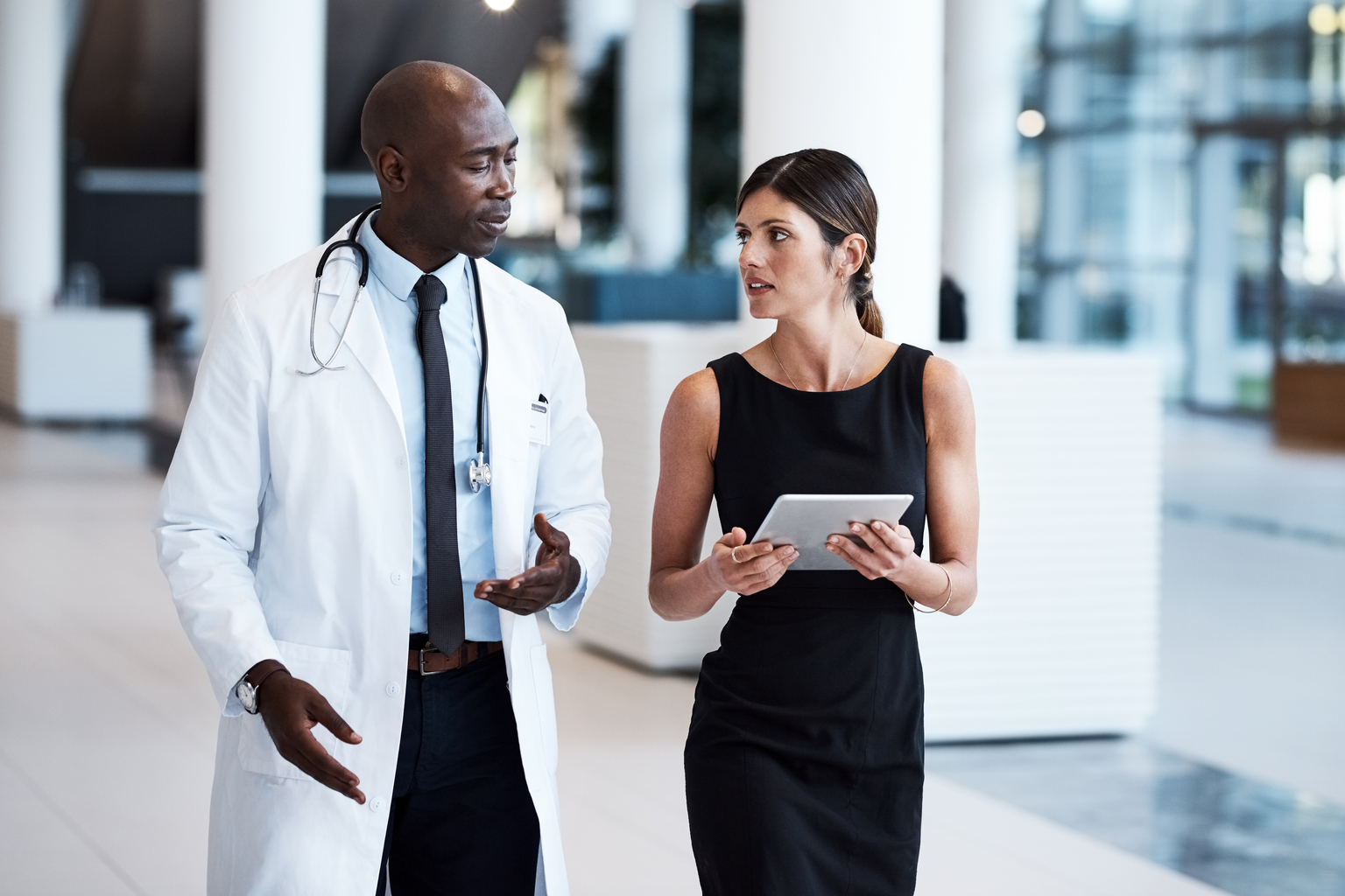 Cropped shot of a handsome male doctor and an attractive young businesswoman looking over a tablet in the hospital