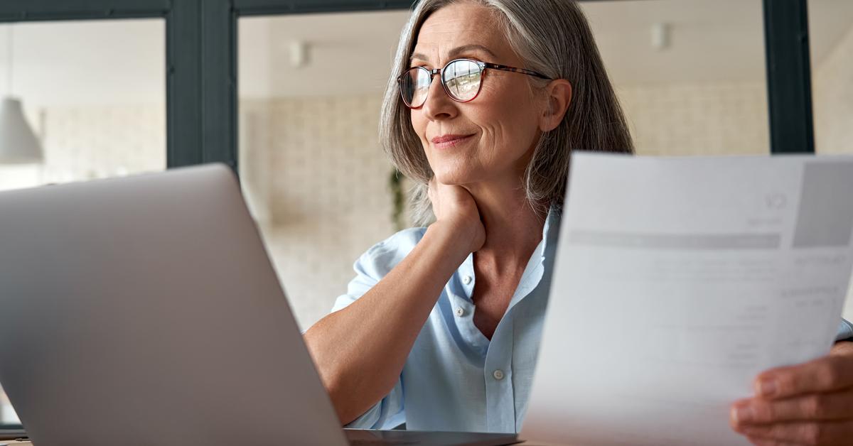 Smiling mature middle aged business woman using laptop working on computer sitting at desk.