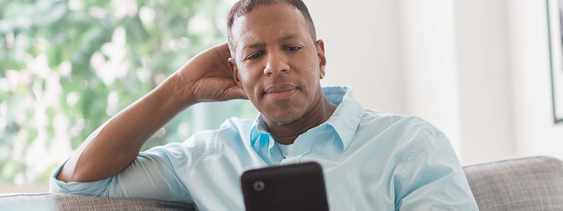 male on couch using tablet