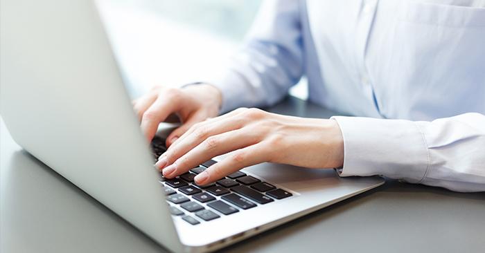 Close up of a person's hands typing on a laptop keyboard