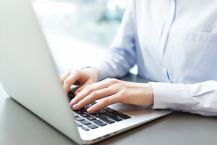 Close up of a person's hands typing on a laptop keyboard