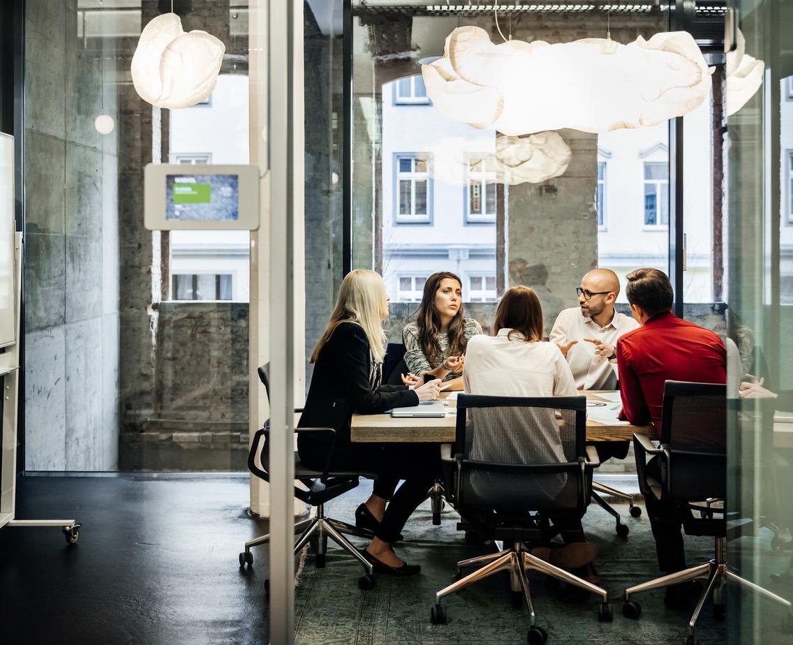 A group of people is sitting at a table during a business meeting in a bright, modern office