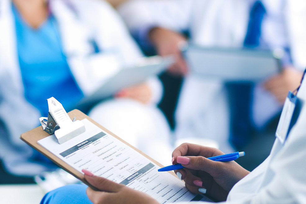 Close up on a few doctors sitting and discussing with clipboards