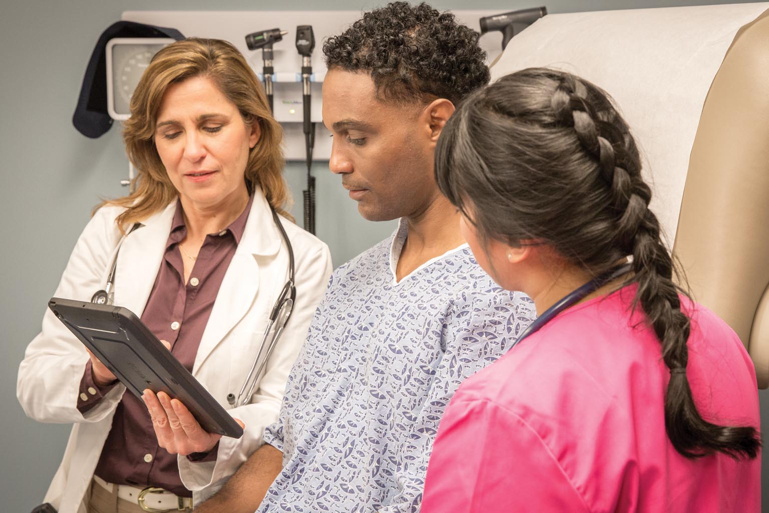 doctor and nurse viewing tablet with patient