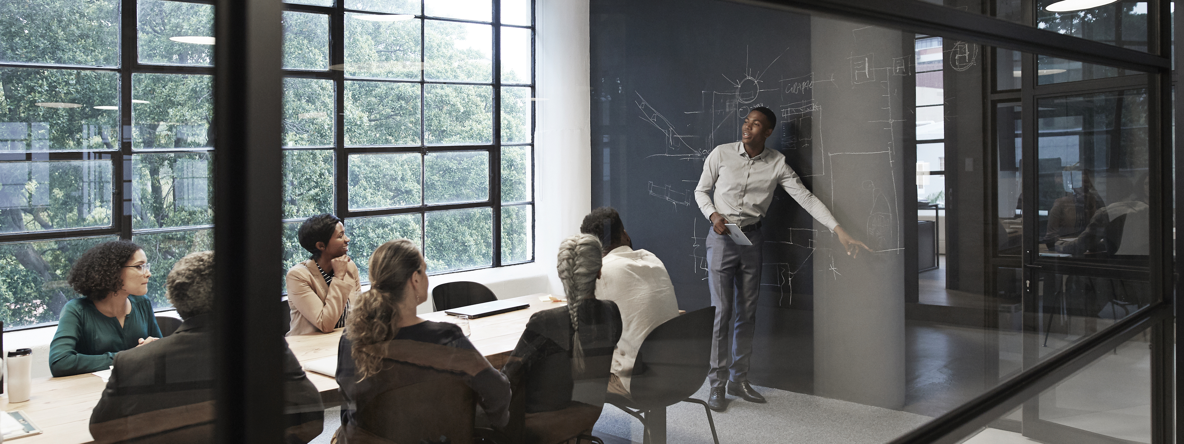 Image of male instructor, discussing , teaching a group of people, or students in a modern conference room pointing at chalkboard, Q3 2021, TAA NA US - Preparer