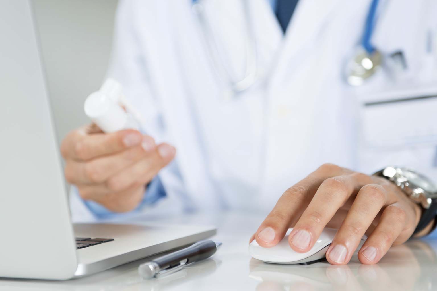 phamacist holding bottle of pills while using computer