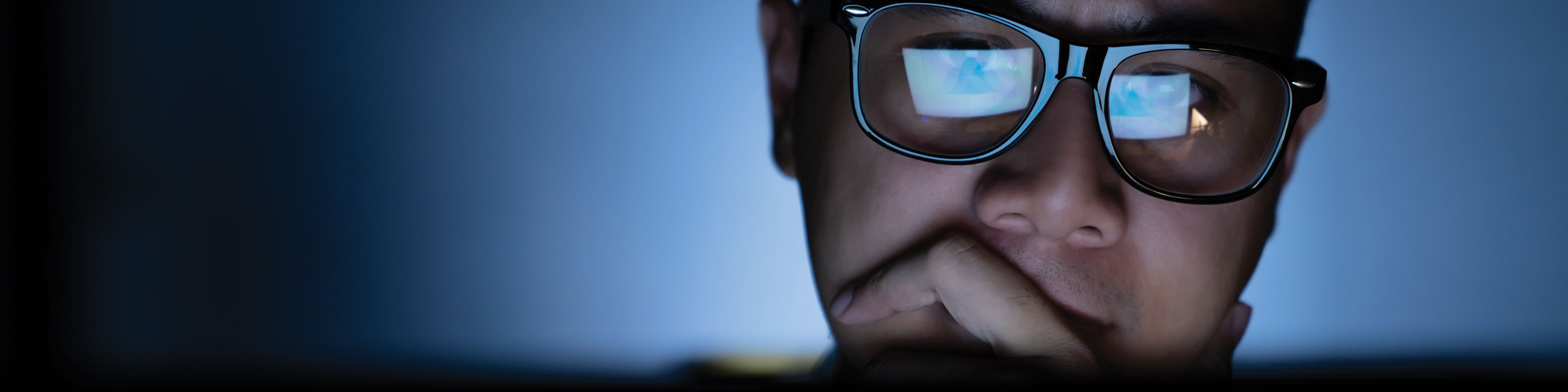 Young Asian man with his laptop reflecting in his glasses