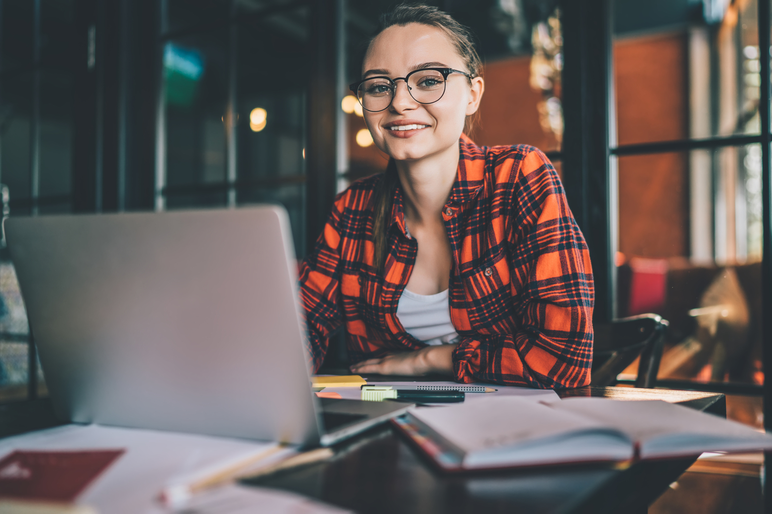 Smiling casual woman with laptop in cafe