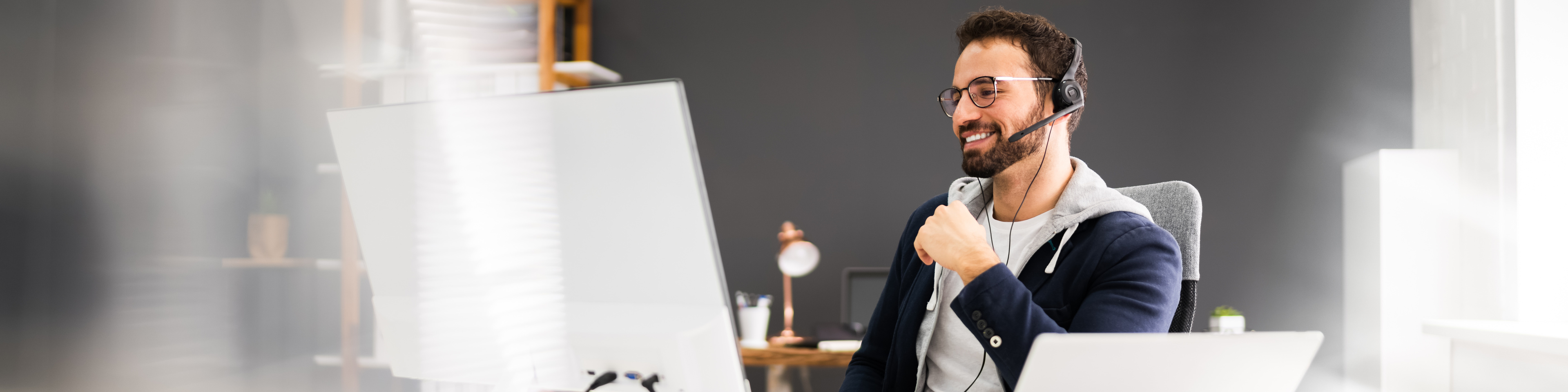 Person sitting at laptop, wearing headset conducting a business call