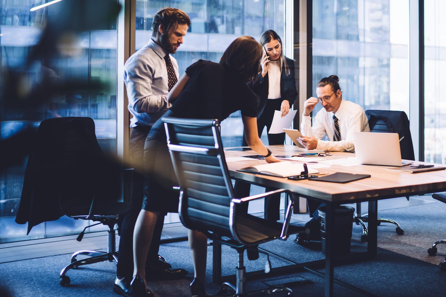 Cooperation process of professional male and female colleagues,business woman in formal suit communicate with operator via smartphone gadget while reading email from partners touch pad during teamwork