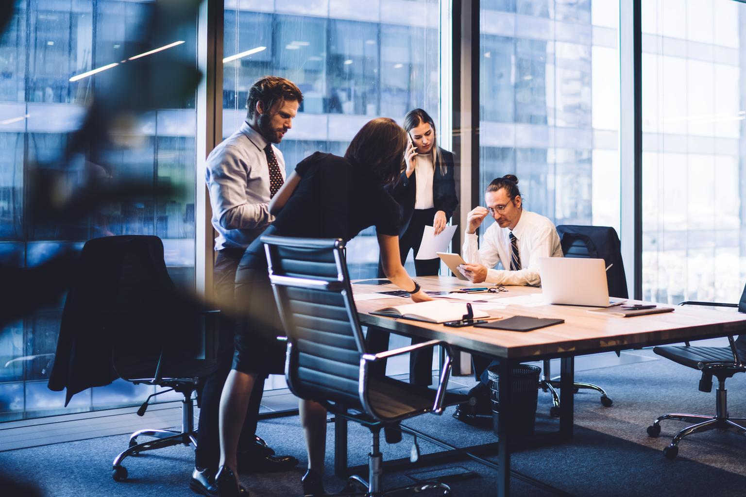 Cooperation process of professional male and female colleagues,business woman in formal suit communicate with operator via smartphone gadget while reading email from partners touch pad during teamwork