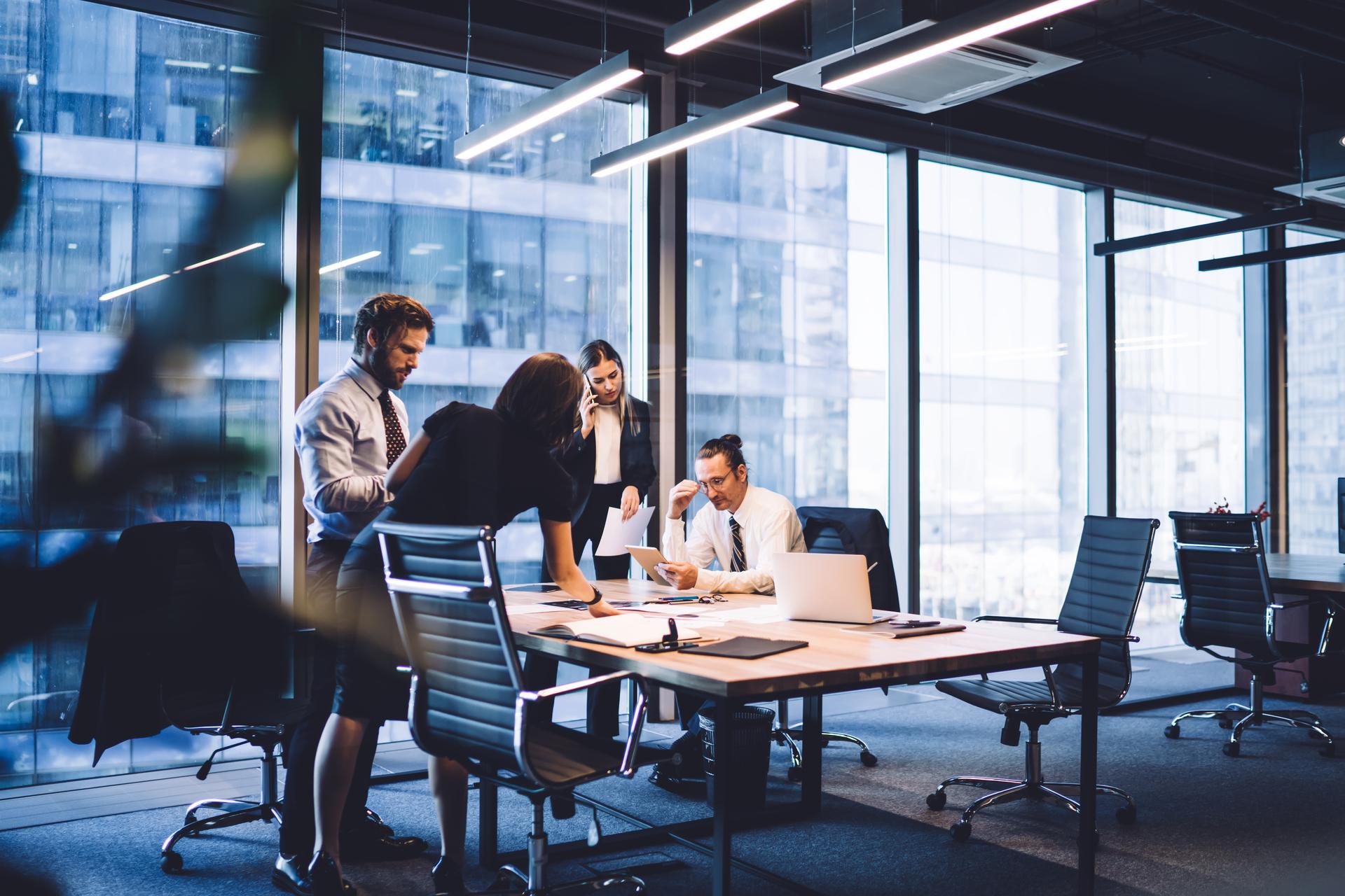 Cooperation process of professional male and female colleagues,business woman in formal suit communicate with operator via smartphone gadget while reading email from partners touch pad during teamwork