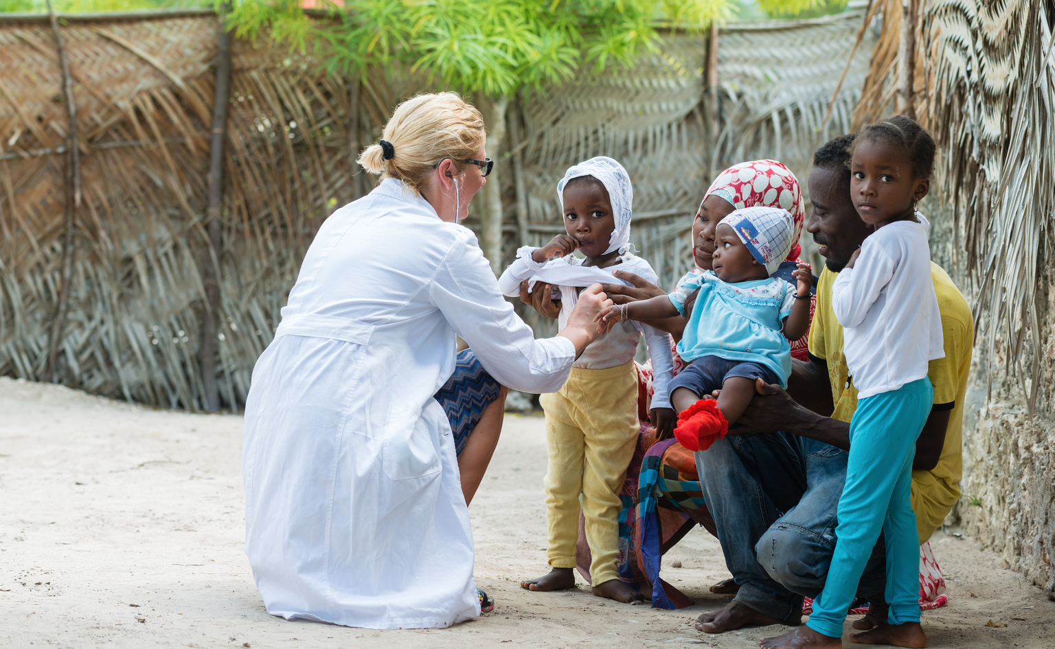 Physician listening to child's heartbeat outdoors 