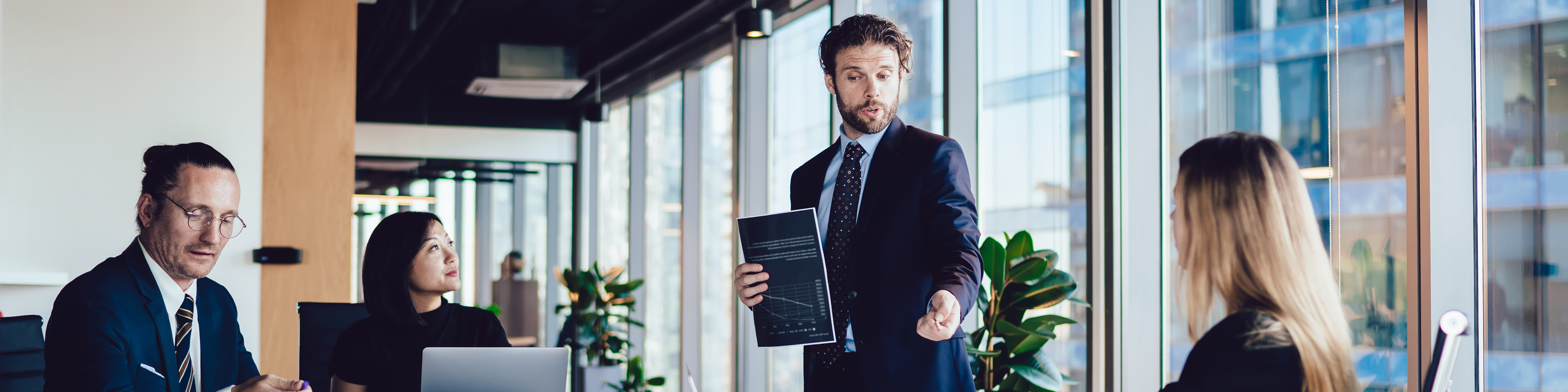 Male CEO with paper document talking to employees