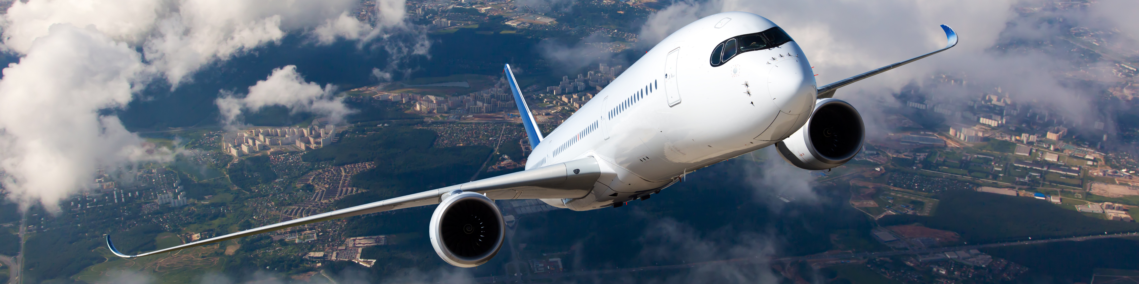 White passenger plane climbs through the clouds. Aircraft is flying high above the city.