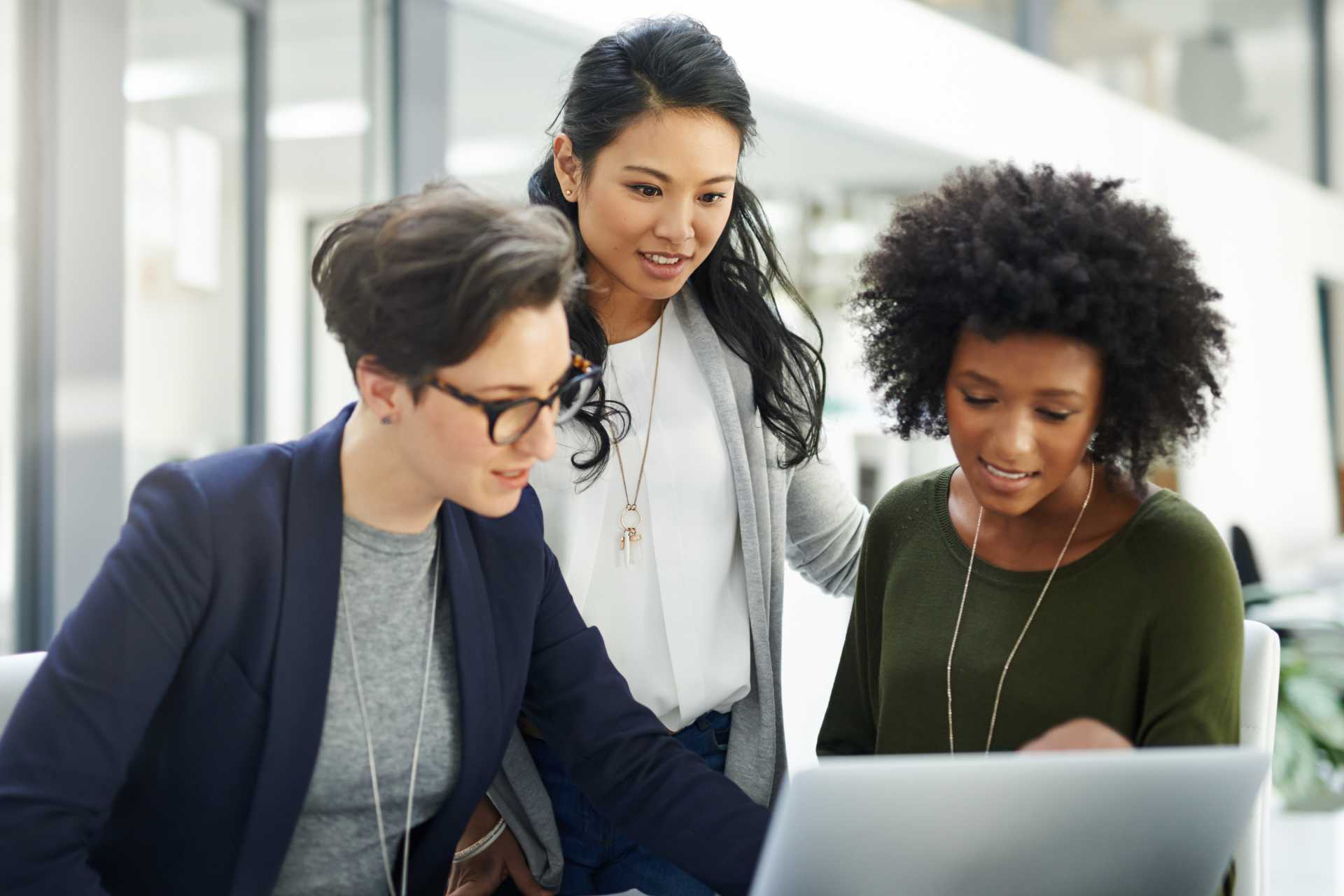 Three young women review laptop