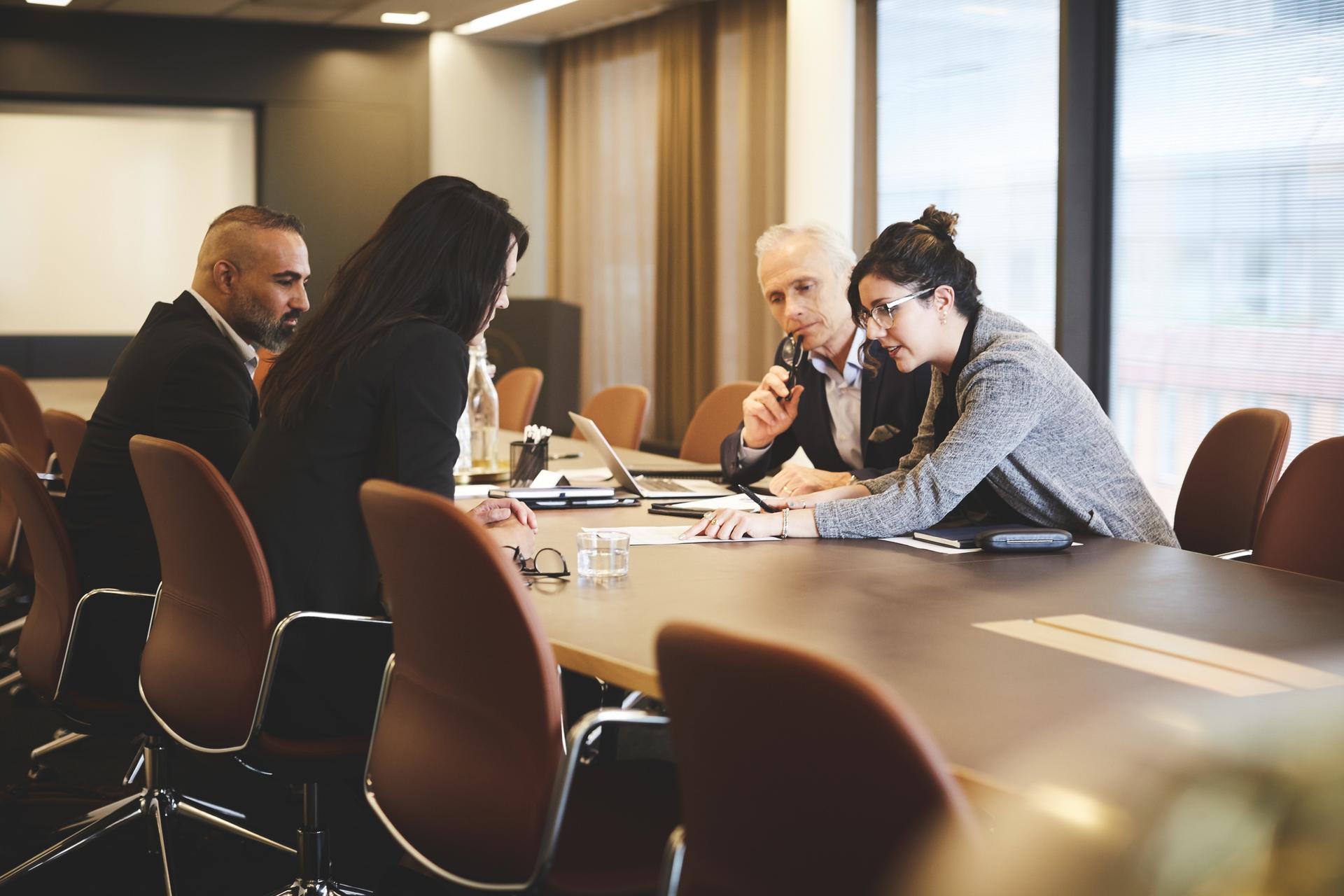 Male and female lawyers discussing over document at conference table in meeting