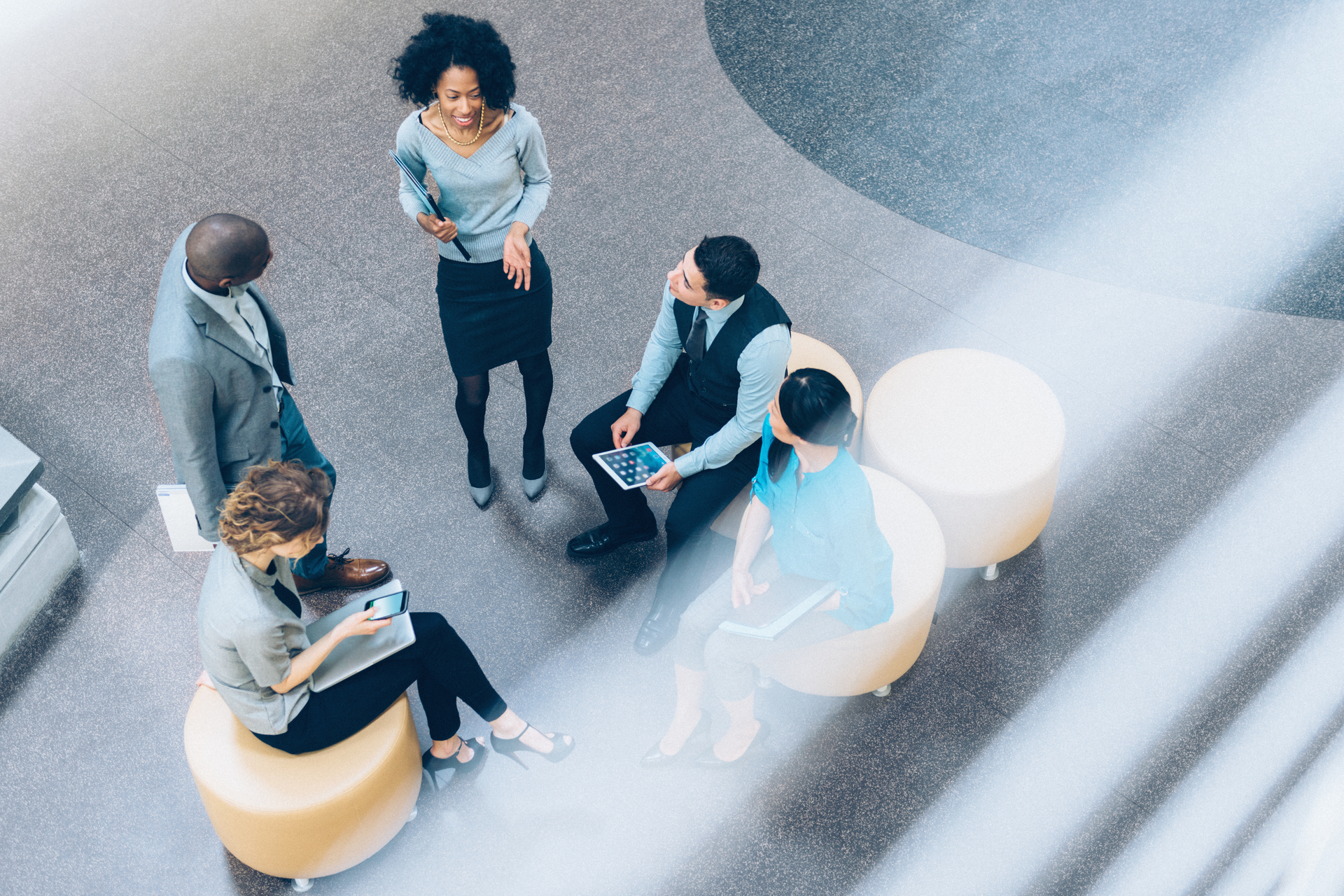 Five people of multiethnic background smiling and talking in the office lobby