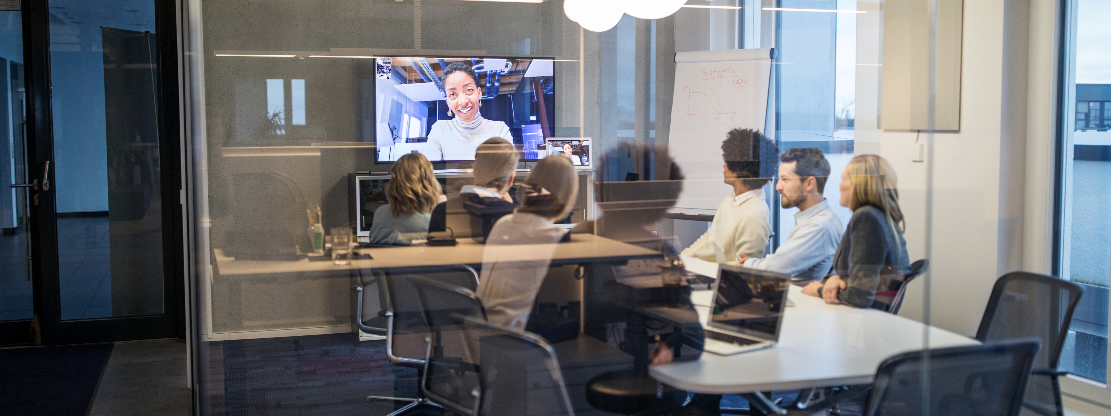 Group of business people having a video conference meeting inside a board room. Businessmen and business women sitting around a conference table talking and networking