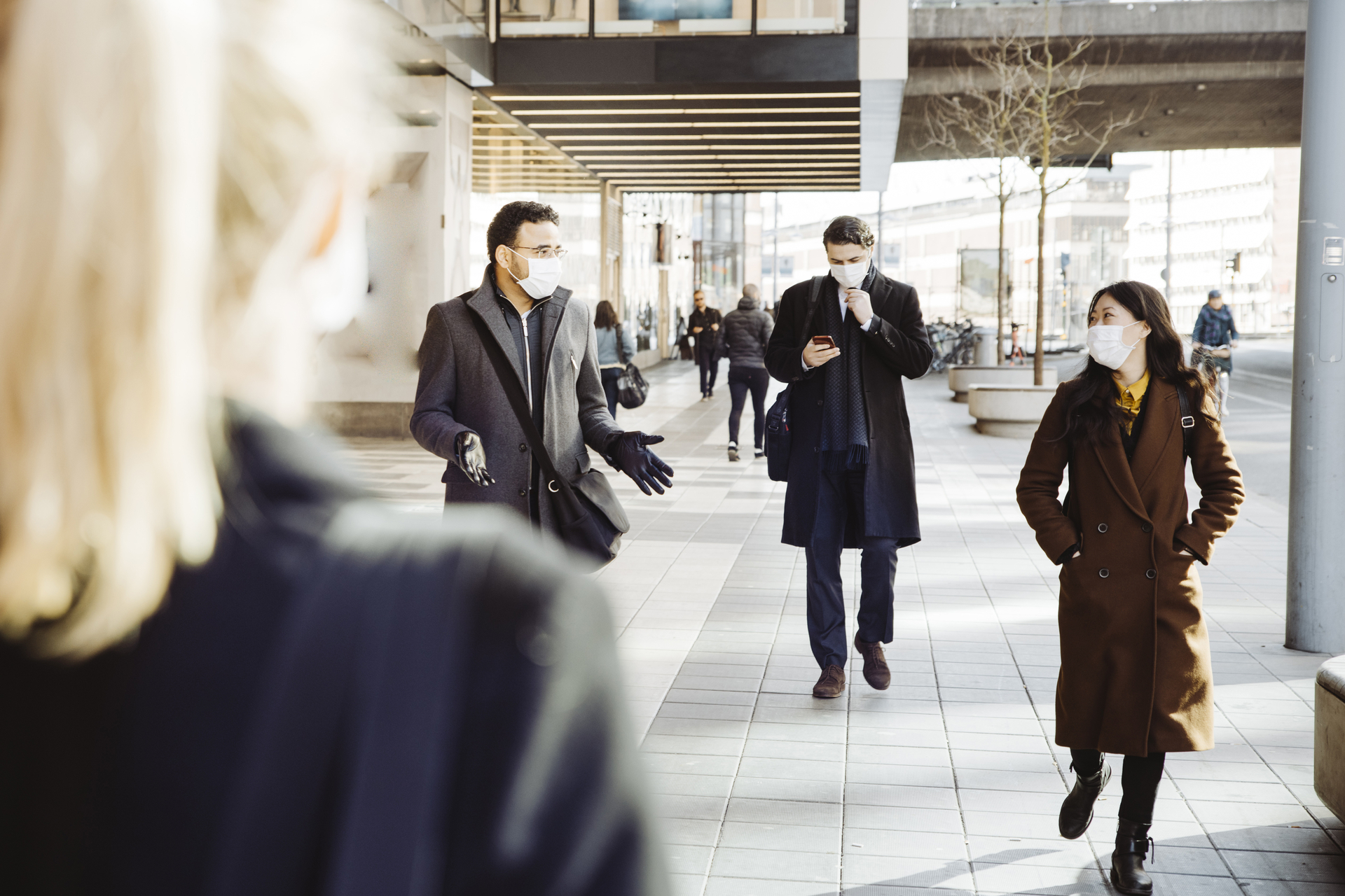 Employees walking and interacting outside the office building wearing a face mask