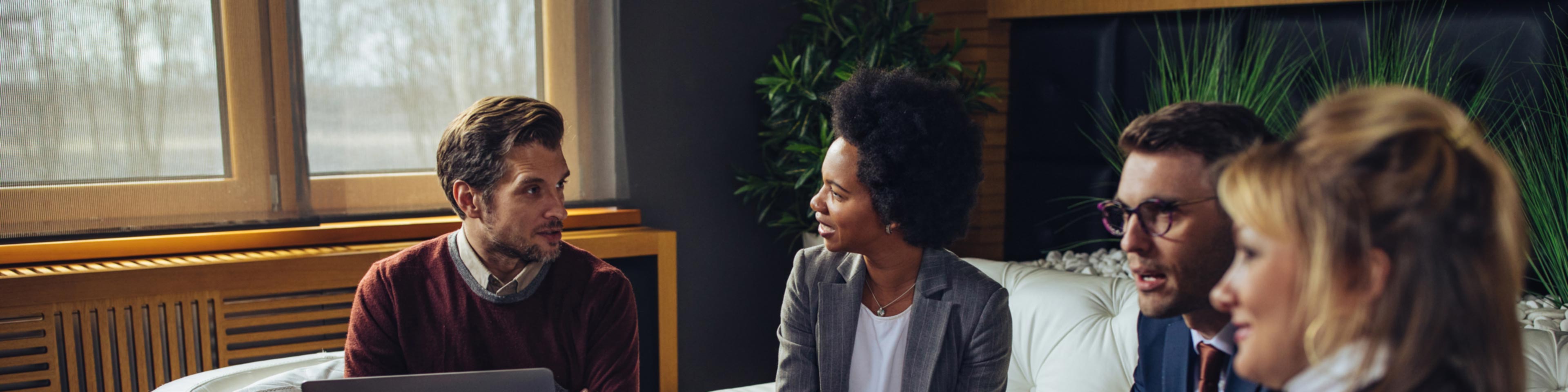 business professionals in conversation sitting down on couches in an office setting