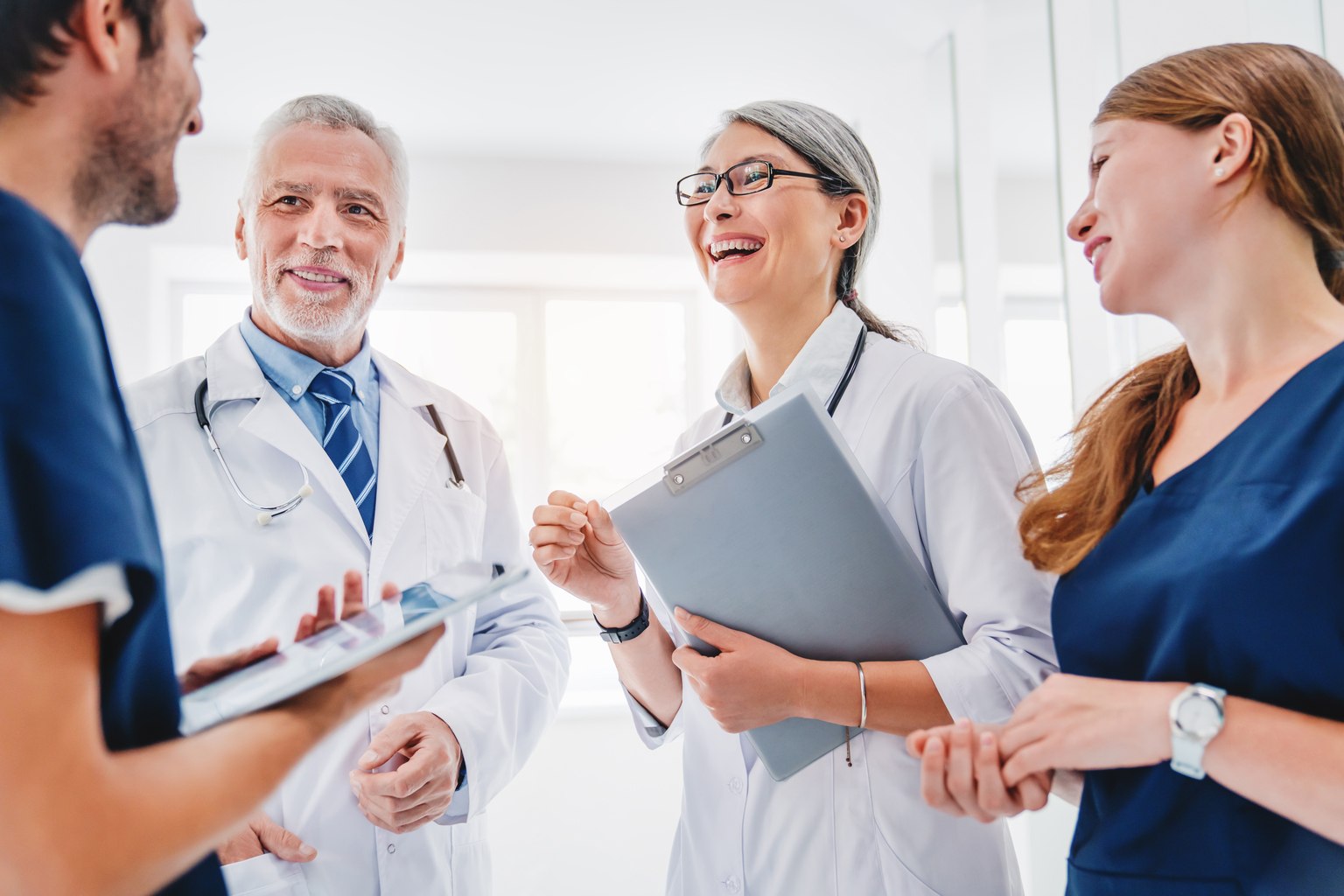 Group of medical professionals and administrators talking and laughing casually together.