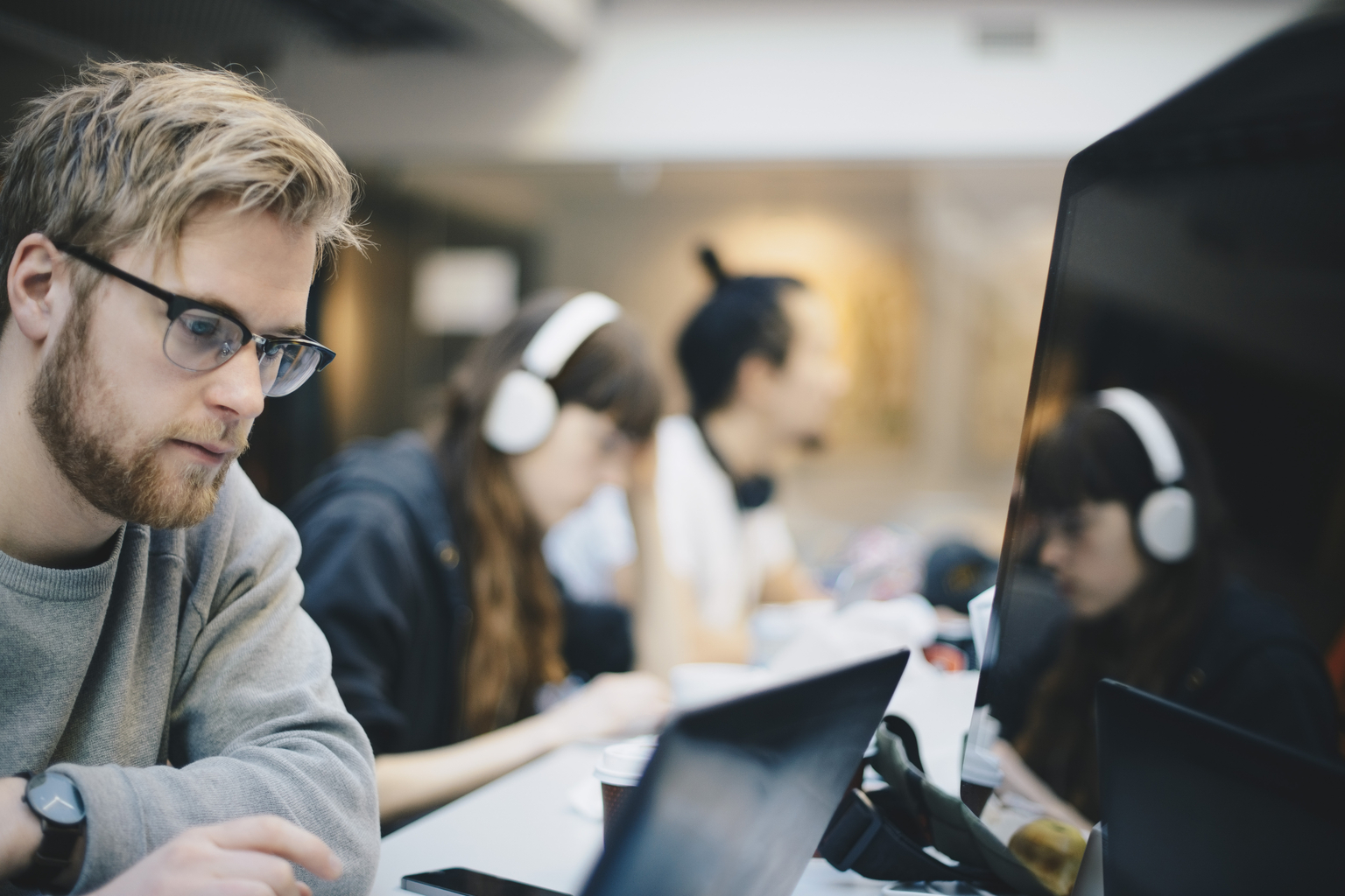 Shot of a young man using a laptop while sitting with his colleagues