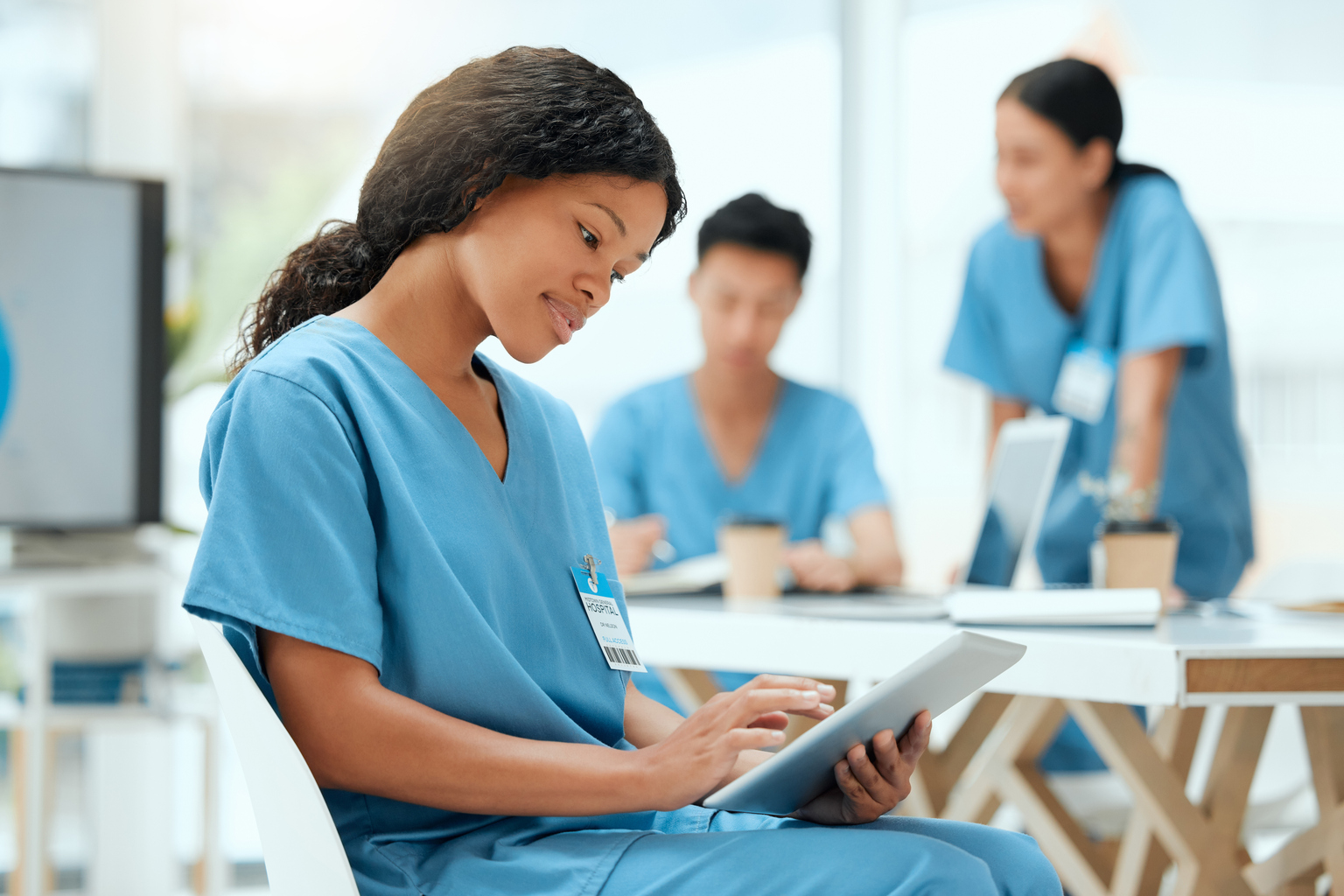 Nursing student reviews class assignment on her tablet while sitting and having coffee