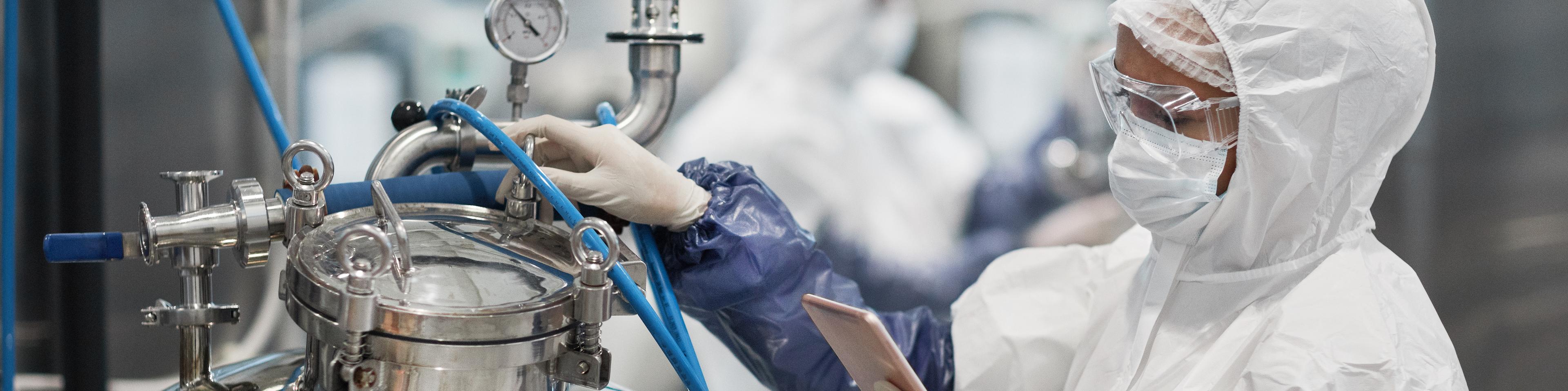 Portrait of female worker wearing protective suit while operating equipment at modern chemical plant, copy space