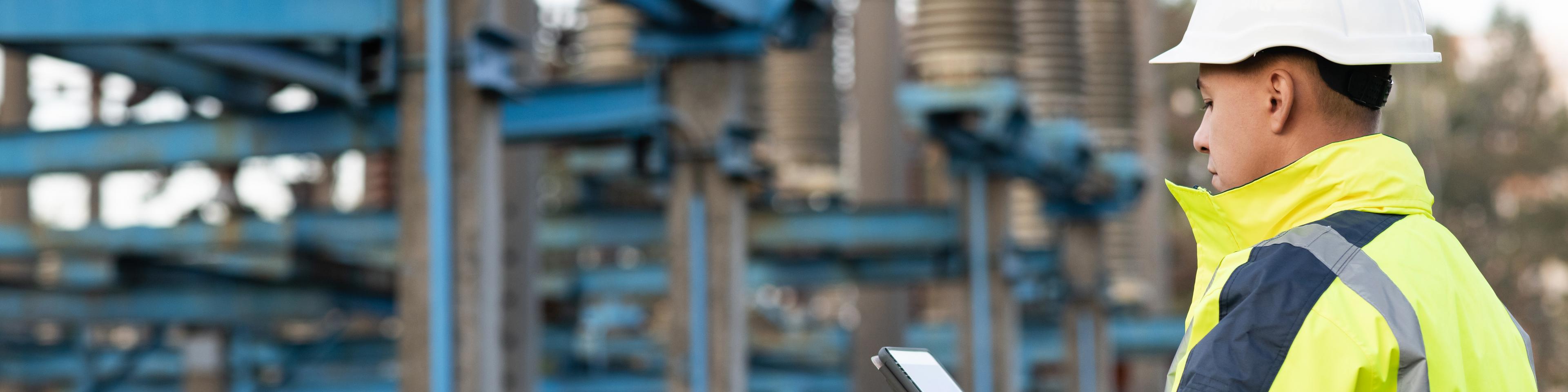 Energy business technology industry concept. Electrical engineer studying reading on tablet. Electrical worker engineer working with digital tablet near tower with electricity