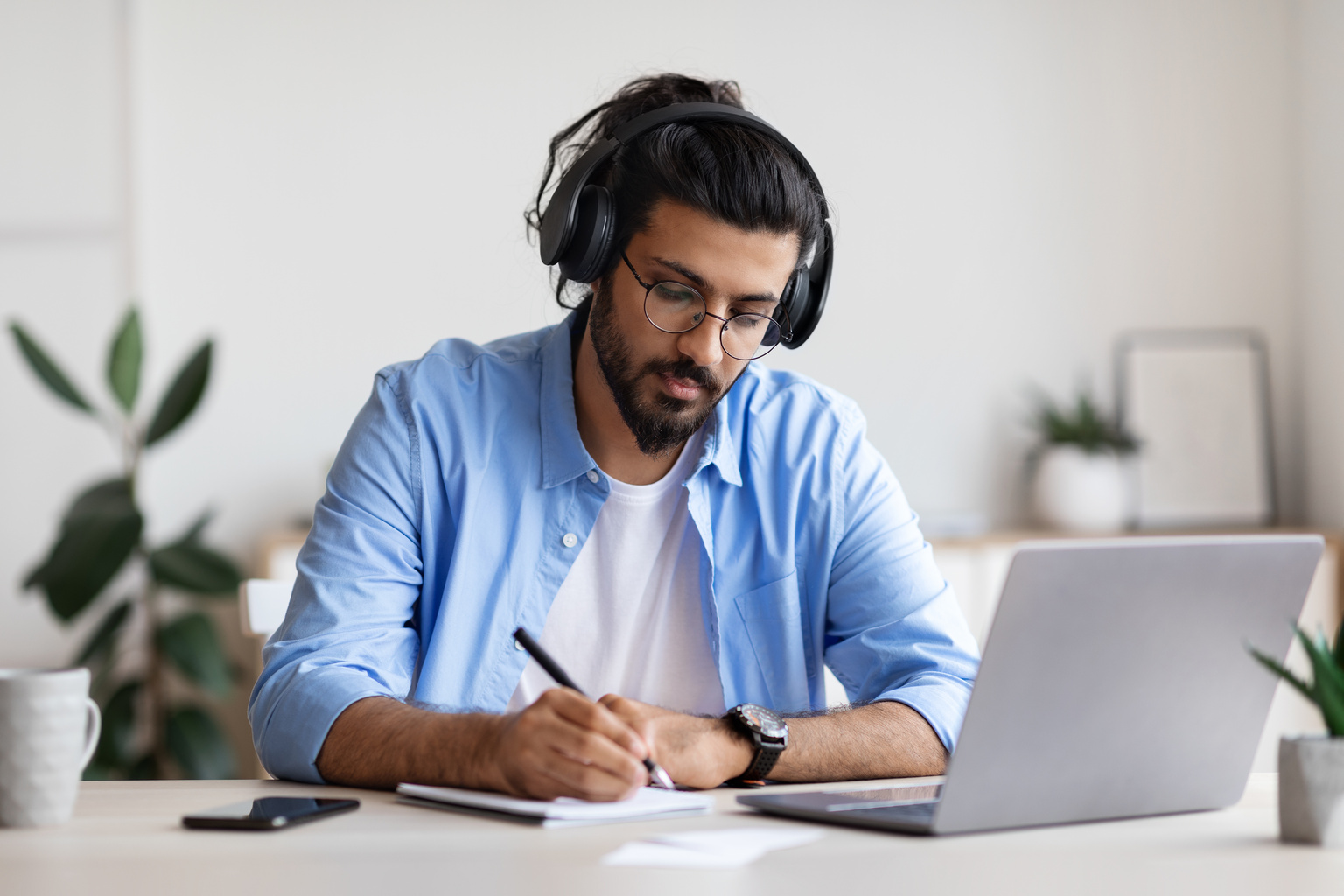 Medical researcher takes notes while referencing material on a laptop