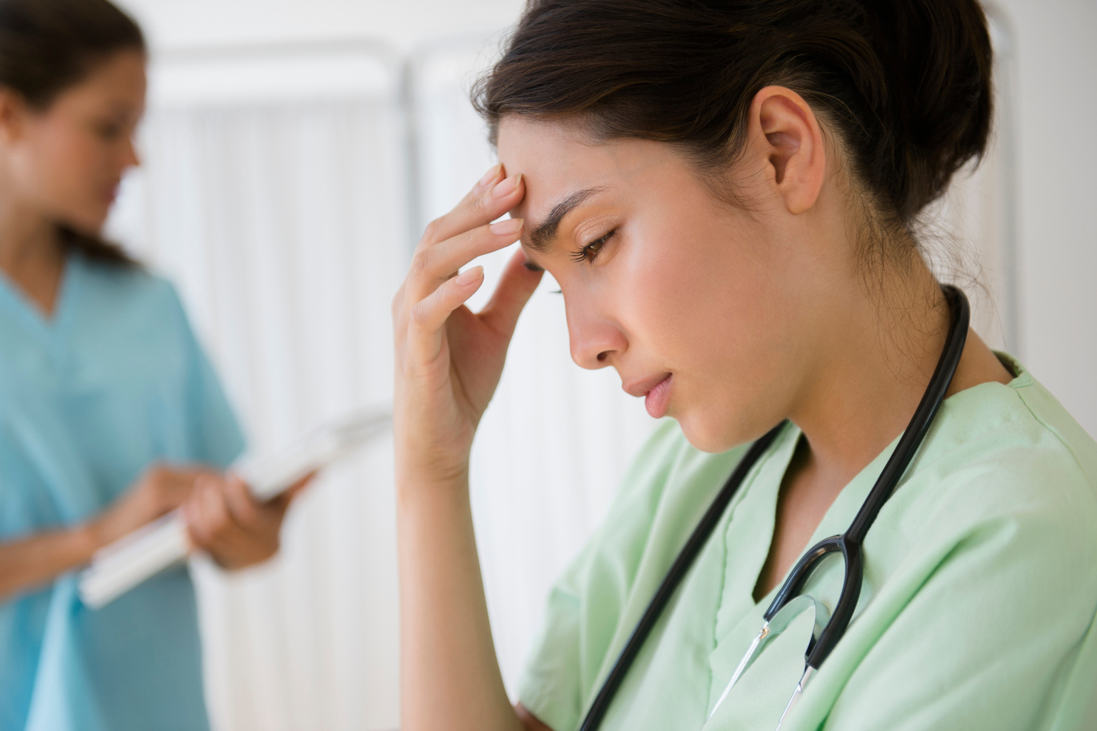 Frustrated nurse holds hand to forehead